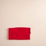Flat lay of high waist black yoga pants in red, neatly folded on a neutral surface.
