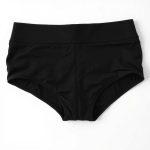 Flat lay of white scrunch butt black yoga pants neatly folded on a neutral surface.