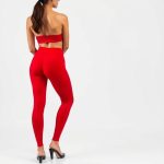 A model wearing high waist black yoga pants in red, showcasing fit from behind on white studio background.