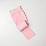 Pastel pink high waist leggings, black yoga pants folded neatly on a neutral surface, top-down view.