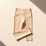 Flat lay of beige high waist tights yoga pants for men neatly folded on a neutral surface.