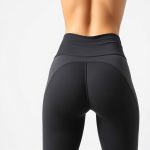 A model wearing high waisted yoga pants women scrunch bum in charcoal, back view, studio shot on white background.