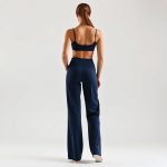 Back view of navy blue wide leg yoga pants with pockets, showcasing fit on model against white studio background.