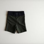Olive green yoga short, black bike shorts with pockets, neatly folded on a neutral surface, top-down view.