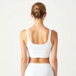 Back view of a model wearing a white yoga singlet yoga sports bra, studio shot on pure white background.