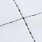 Close-up of the black cross top fabric texture, stitching, and recycled materials.