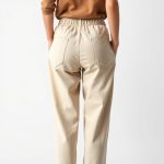 Back view of a model wearing black jogger pants womens lounge pants pockets in beige, studio shot on white background.