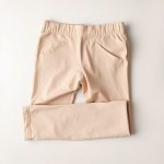 Flat lay of beige straight leg yoga pants, black leggings with pockets, neatly folded on a neutral surface.