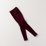 Burgundy black seamless leggings with pockets, folded neatly on a neutral surface, top-down flat lay view.