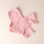 Pastel pink flared leggings women invisible scrunch leggings folded neatly on a neutral surface, top-down view.