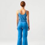 Back view of a model in sky blue flared yoga pants and a matching yoga tank top on a white background.