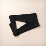 Black leggings with pockets workout pants neatly folded on a neutral surface, top-down view.