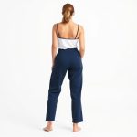 Back view of a woman in navy blue bamboo loose exercise pants on a white background.