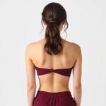 Back view of a model wearing the ceremony cacao wrap crop top in burgundy.