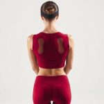 Back view of a model in a red yoga crop top and black soft headband on a white background.