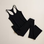 Neatly folded black yoga tank top and flare leggings in a minimalist flat lay.
